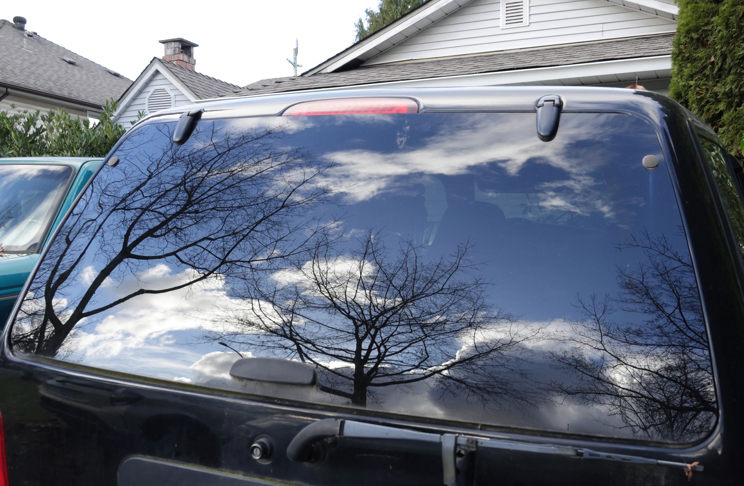 Glossy vehicle window reflecting trees and sky after exterior detailing