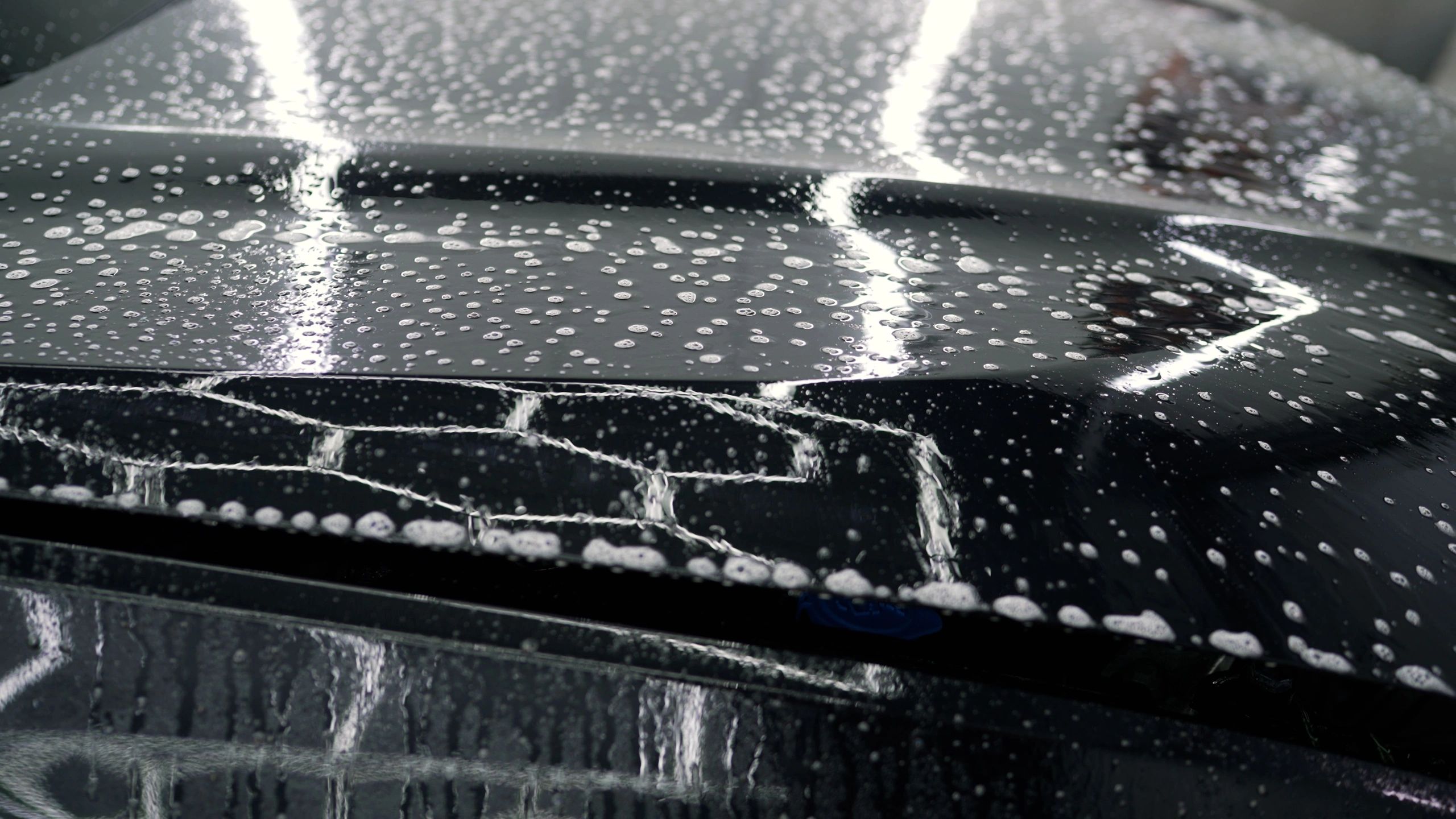 Professional detailer applying foam to a vehicle hood during detailing preparation